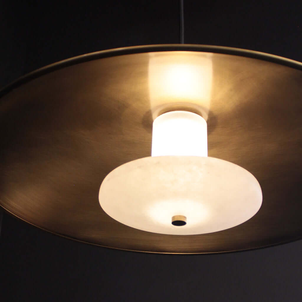 Close-up of a pendant light with a gold finish and white bulb on a dark background