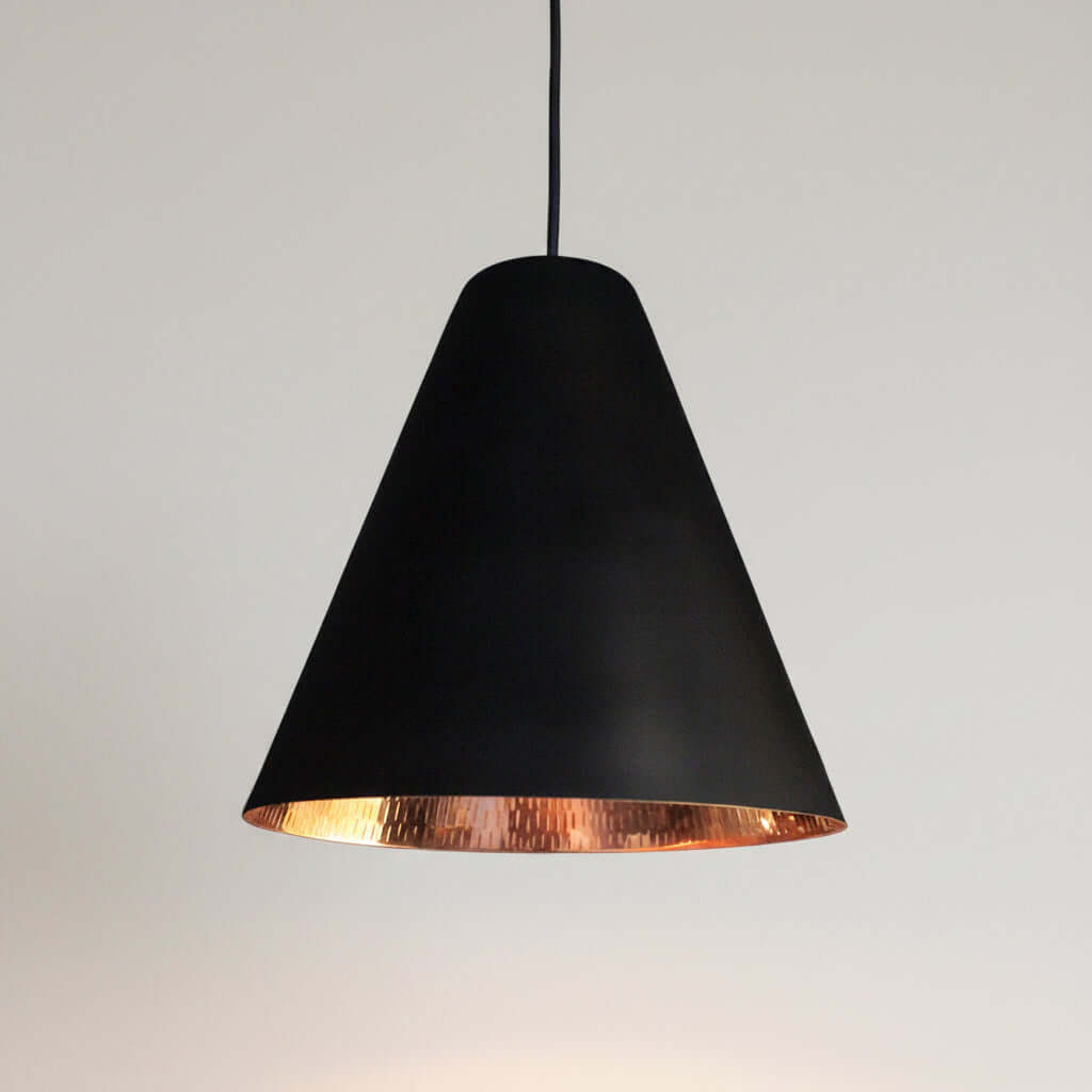 Black pendant light with copper interior on a white background