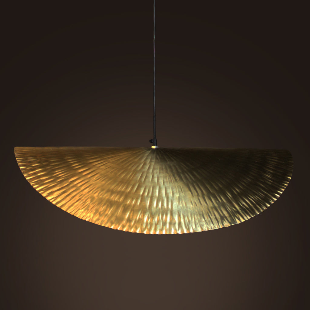 Gold semi-circular pendant light against a dark background