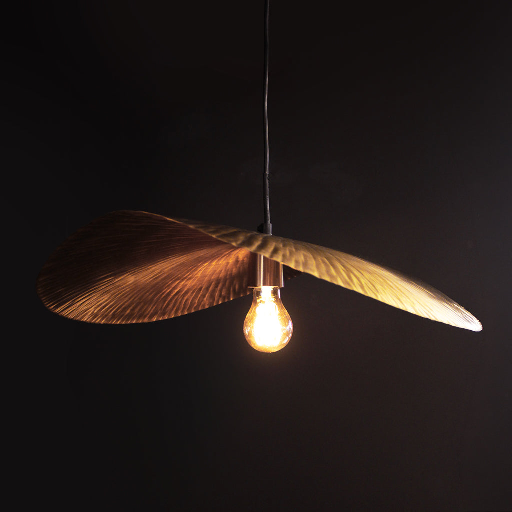 Decorative pendant light with leaf-like design and illuminated bulb against a dark background