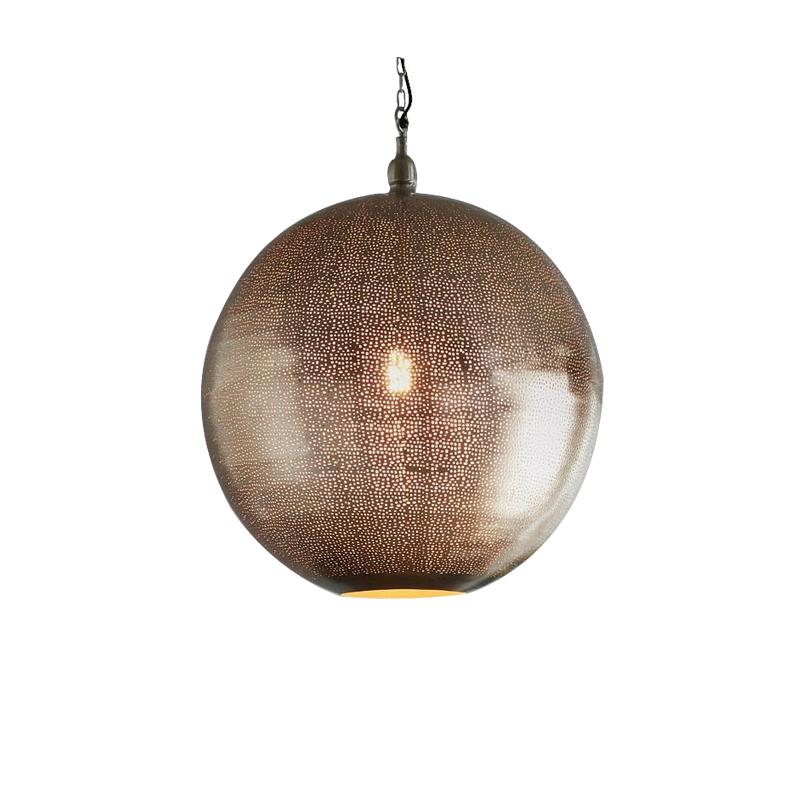 A modern pendant light with a nickel finish and small perforations in the shade, suspended over a grey table, featuring two plants and a geometric metal leg.