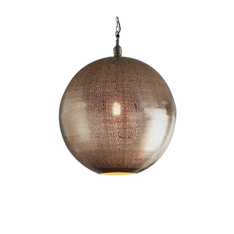 A modern pendant light with a nickel finish and small perforations in the shade, suspended over a grey table, featuring two plants and a geometric metal leg.