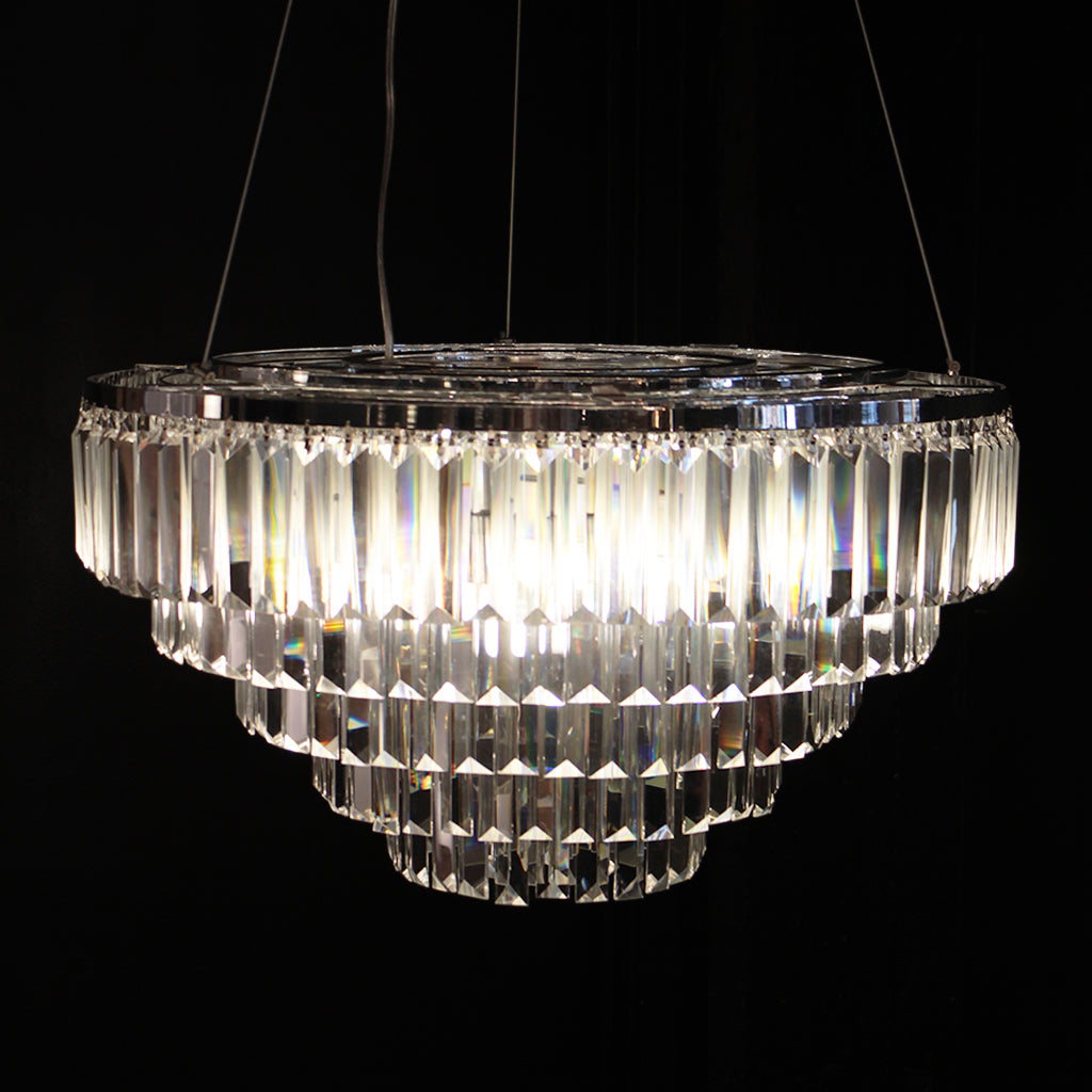 A tiered chandelier with clear prism crystals on a polished silver frame against a black background