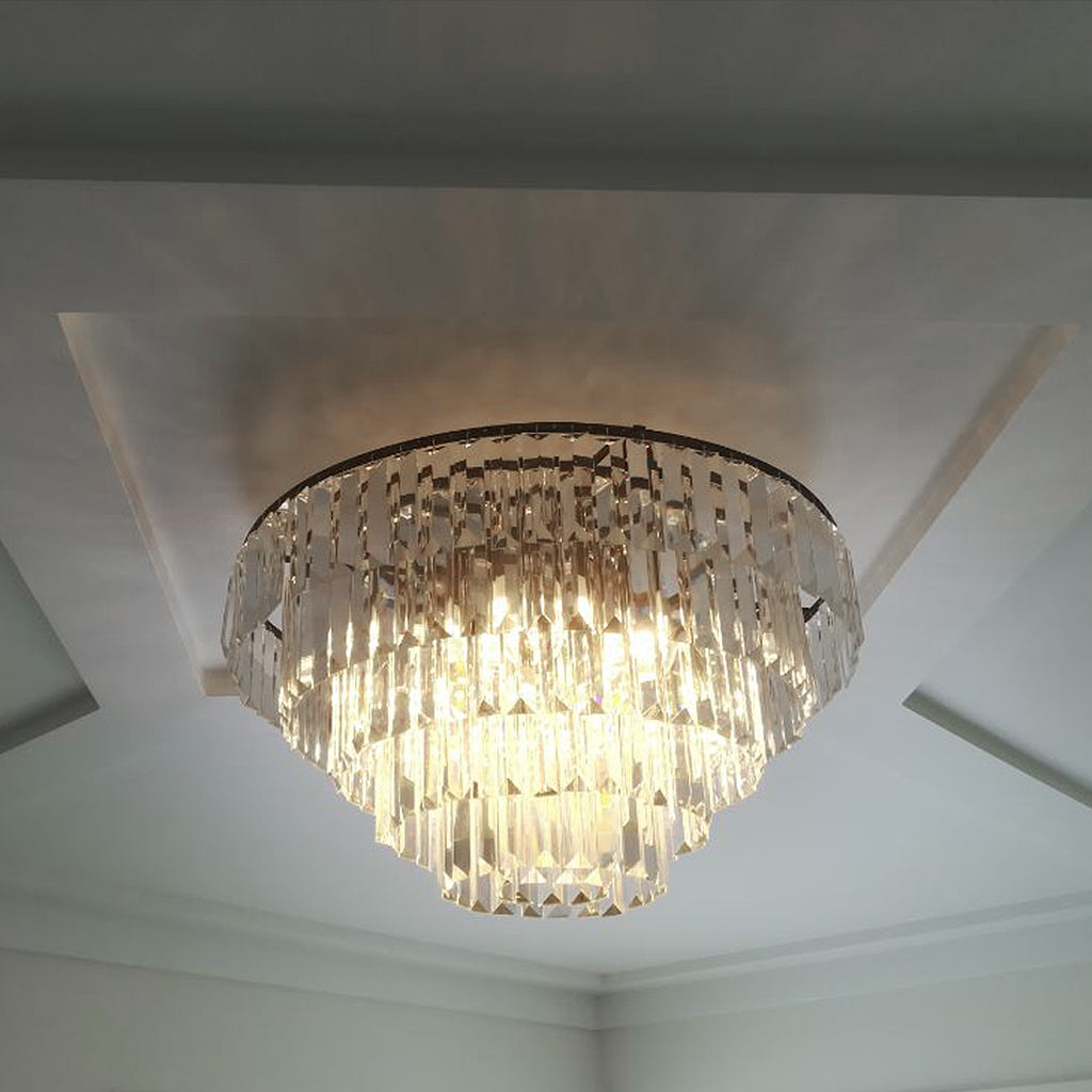 A tiered chandelier with clear prism crystals on a polished silver frame against a black background