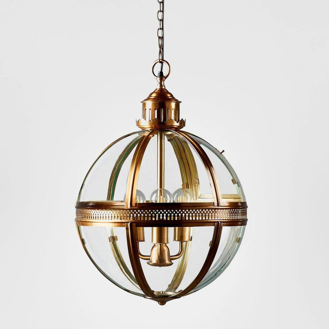 A spherical pendant light fixture with a clear glass globe and ornate brass-toned metal frame, suspended by a chain against a light gray background.