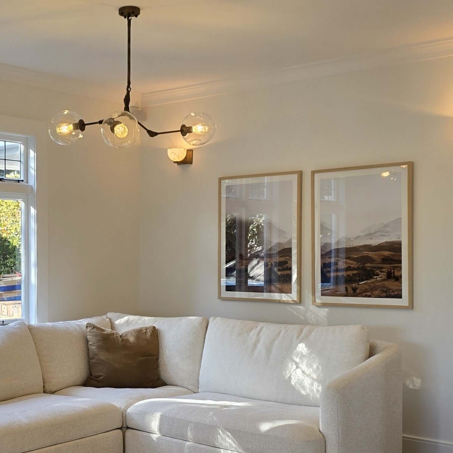 Living room with a white sofa, chandelier, and framed pictures on the wall.