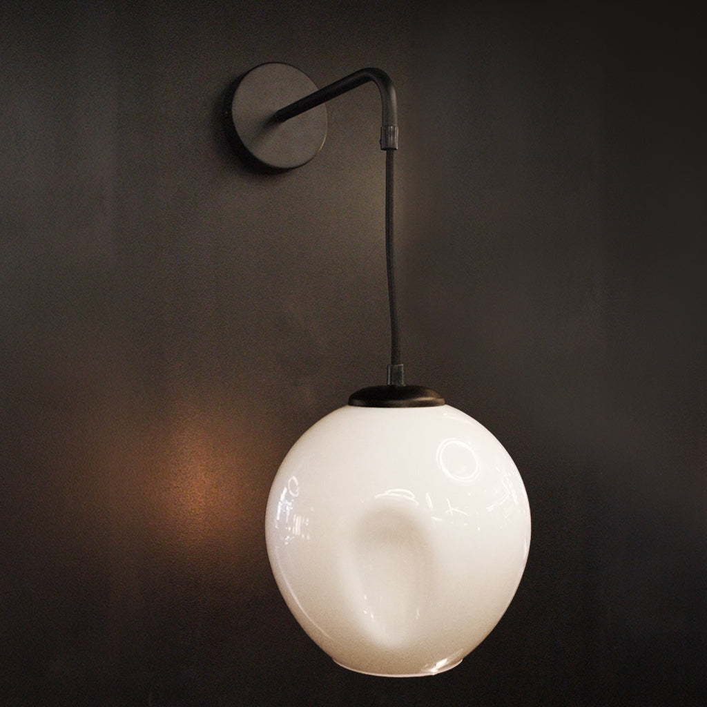 Tapering White glass pendant lightshade on wall mounted bracket against dark background
