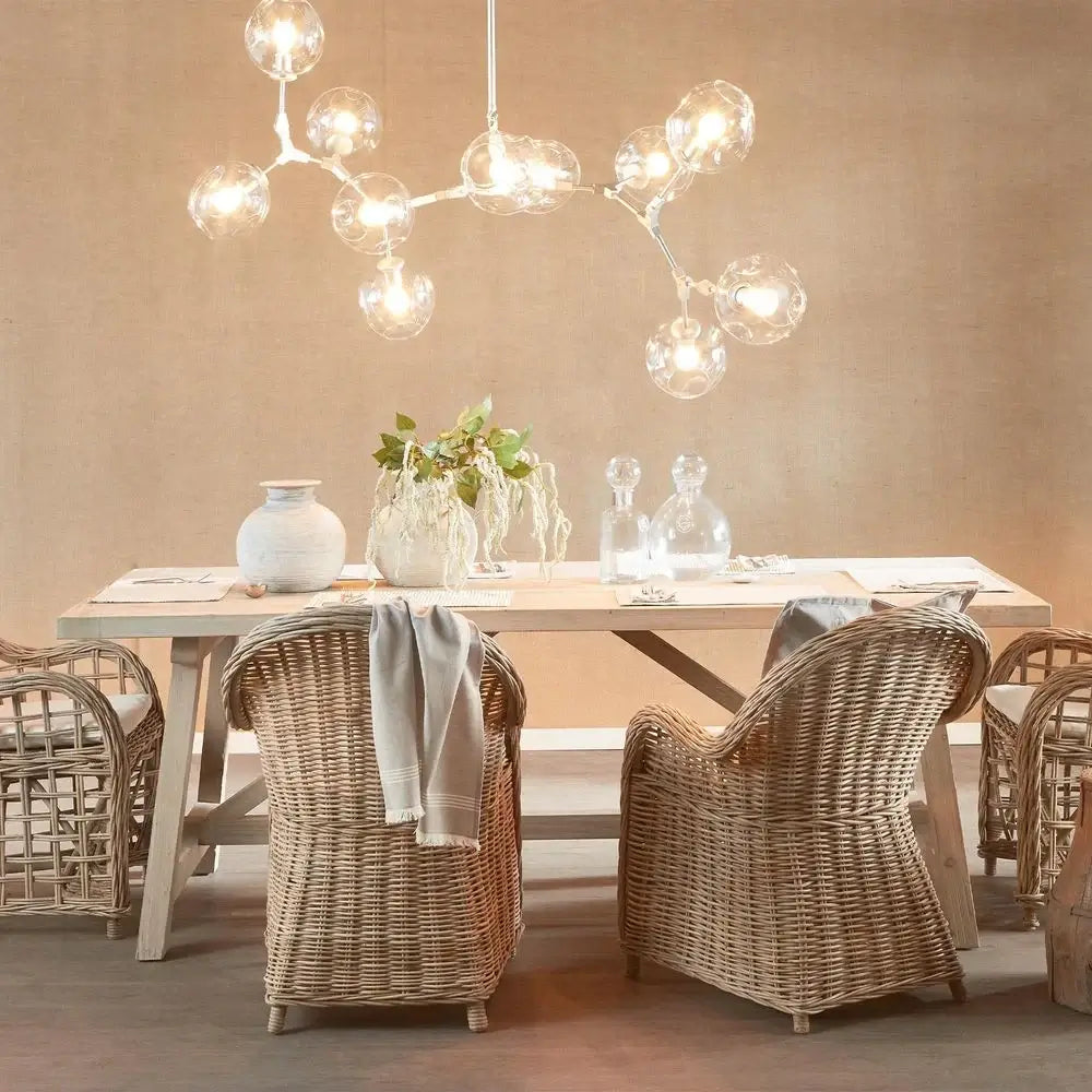 Dining room with wooden table and wicker chairs under a modern chandelier.