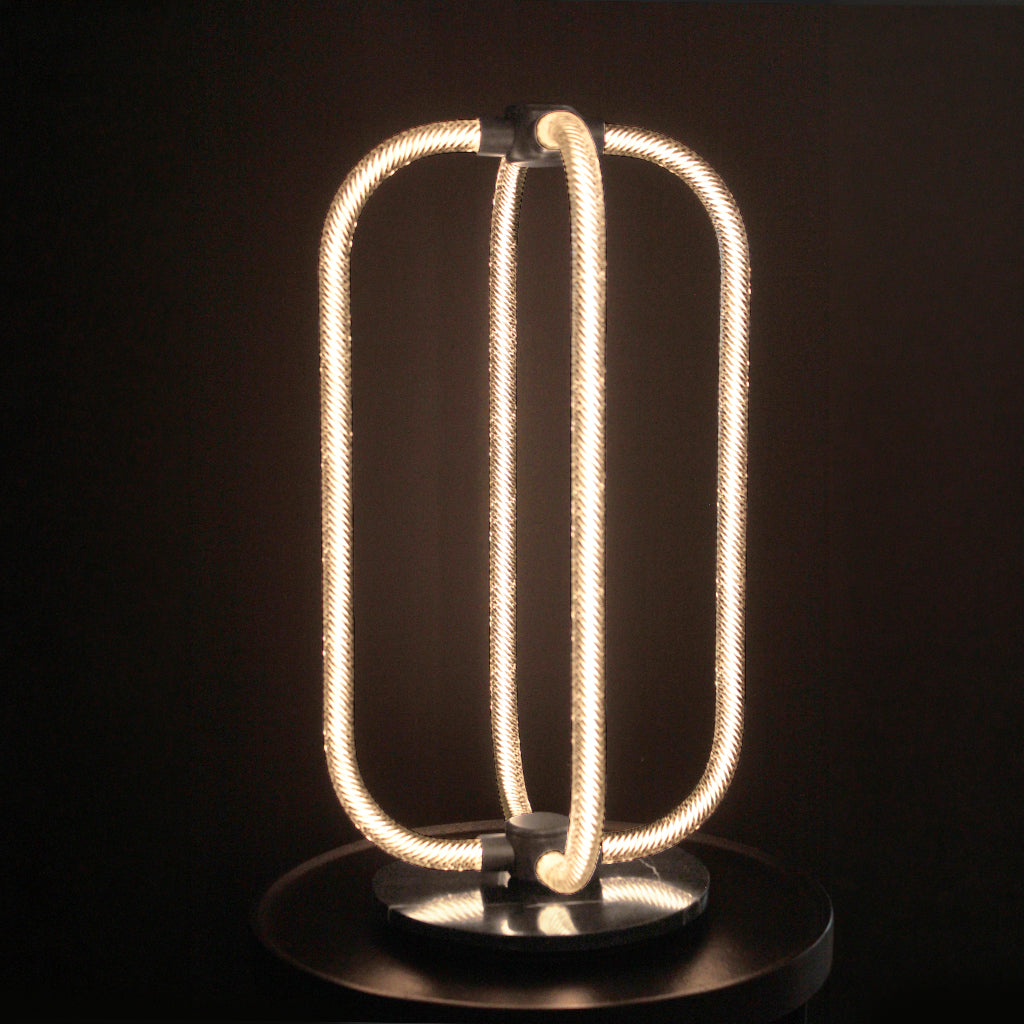Modern LED table lamp with coiled design on a dark background