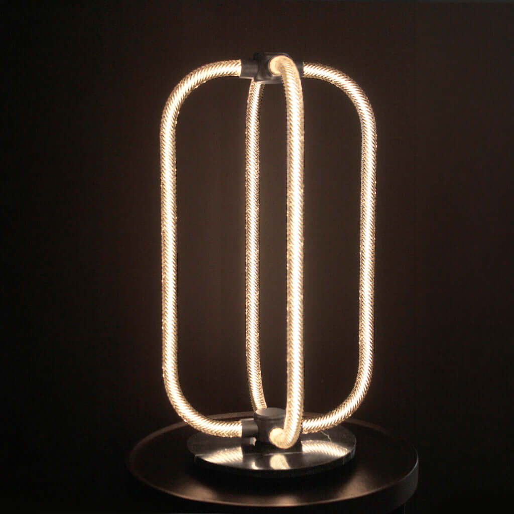 Modern LED table lamp with coiled design on a dark background