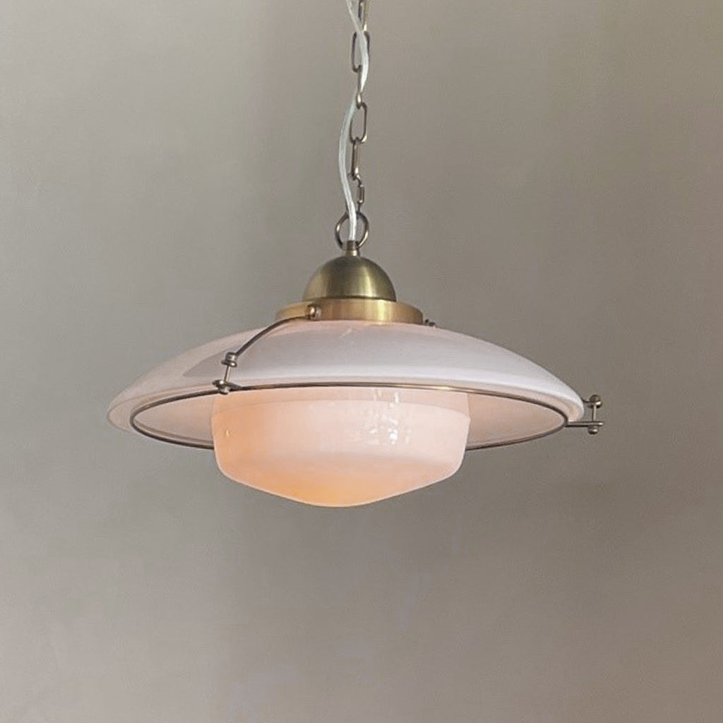 Vintage-style pendant light with a white shade and brass fixture on a plain background