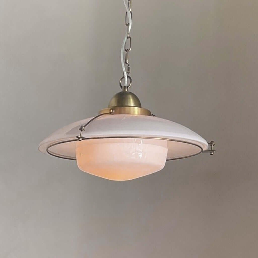 Vintage-style pendant light with a white shade and brass fixture on a plain background