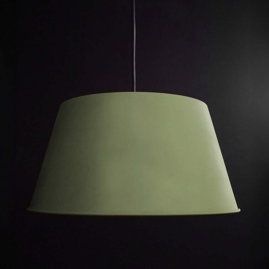 Green pendant lamp with a lit bulb against a black background