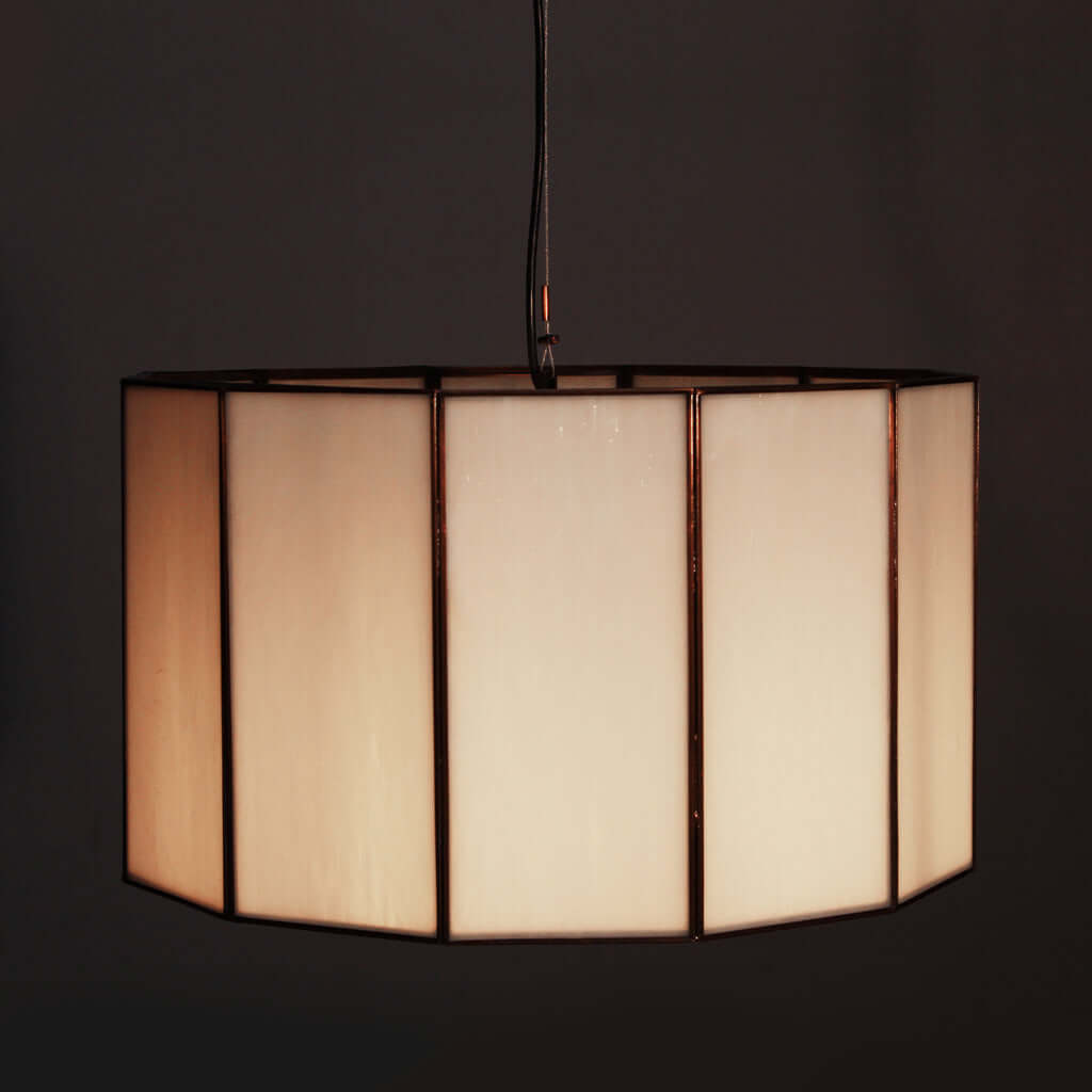 Glass and bronze pendant light with a geometric pattern on a dark background