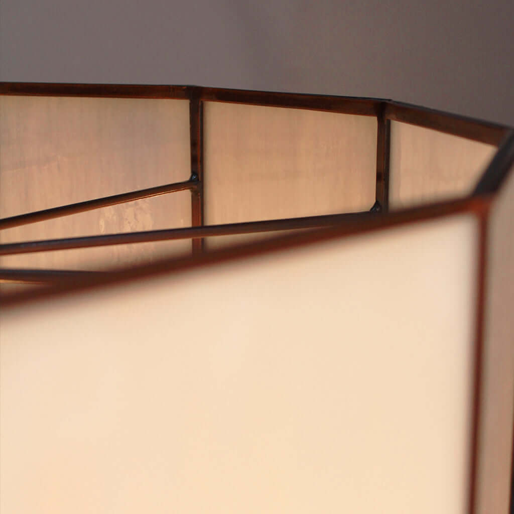 Close-up of a lamp with a white glass shade and metal frame against a neutral background