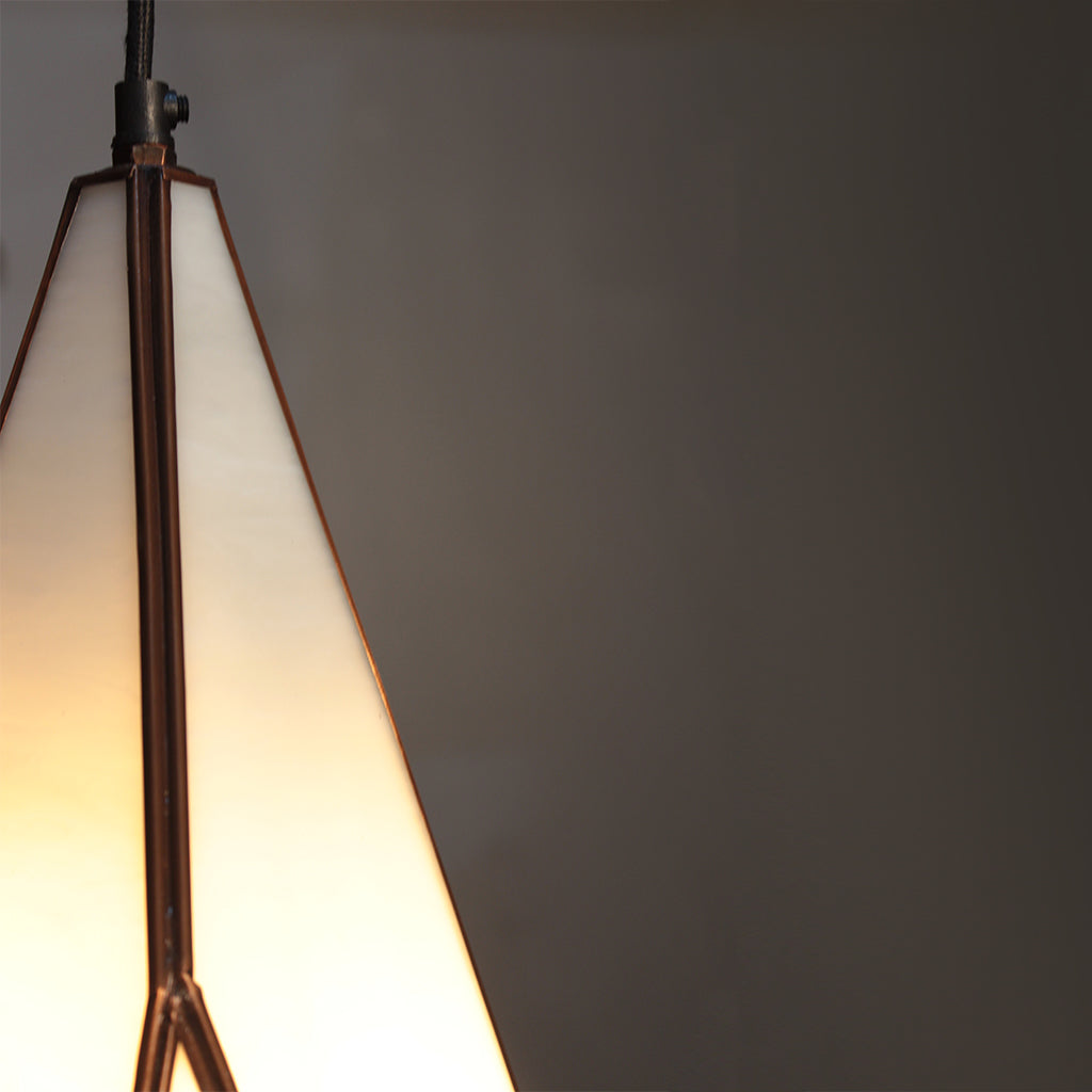 Close-up of a pendant light with a gradient from white to warm yellow against a dark background