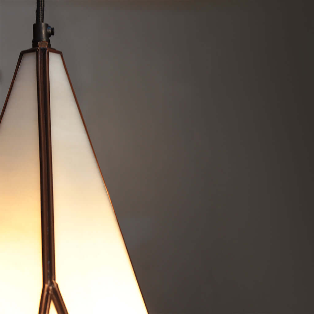 Close-up of a pendant light with a gradient from white to warm yellow against a dark background