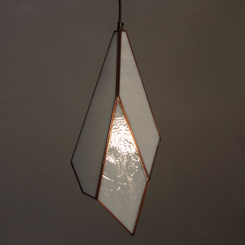 Geometric pendant light with a white glass shade on a dark background