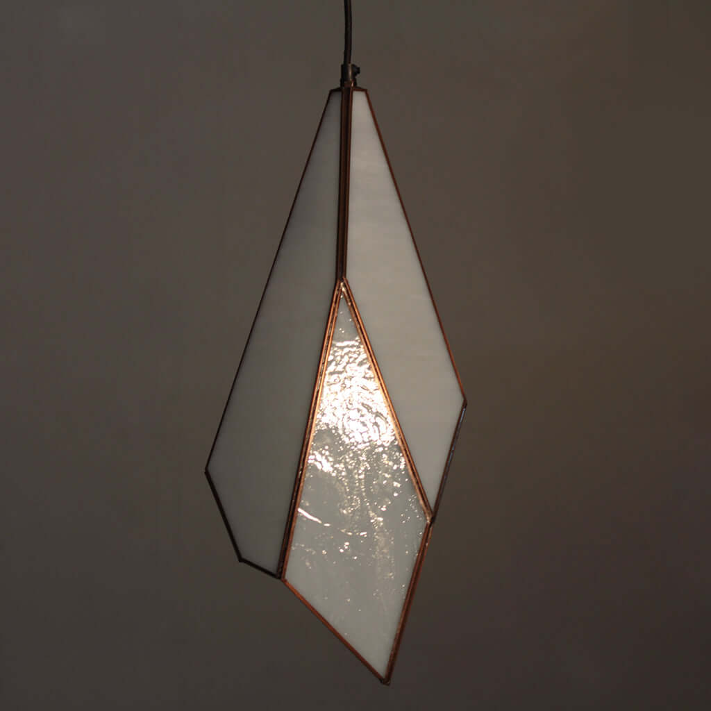 Geometric pendant light with a white glass shade on a dark background
