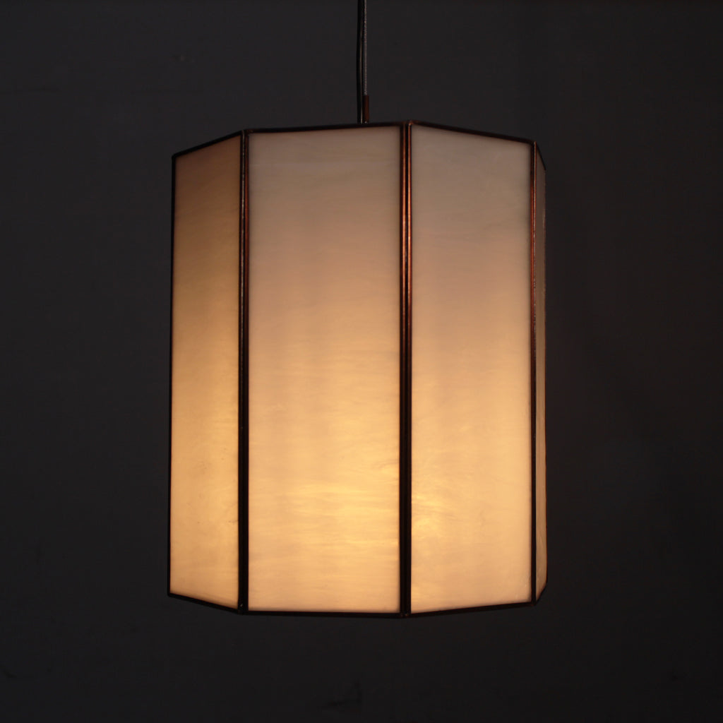Hexagonal lampshade with a warm glow on a black background