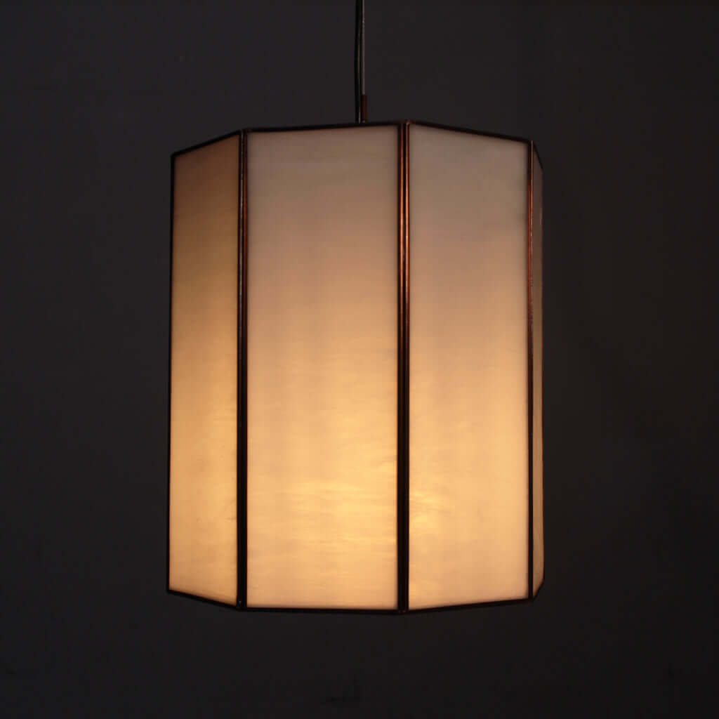 Hexagonal lampshade with a warm glow on a black background