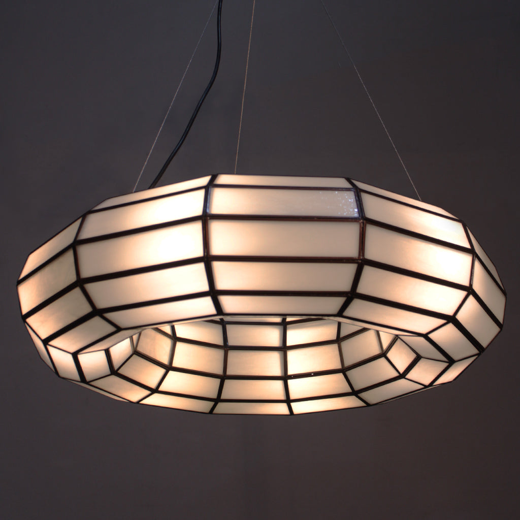 Handmade glass pendant light with a geometric pattern on a dark background