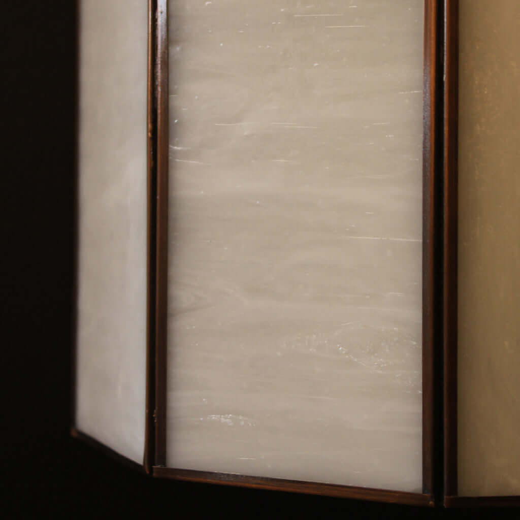 Close-up of a light fixture with a textured glass cover and metallic frame.