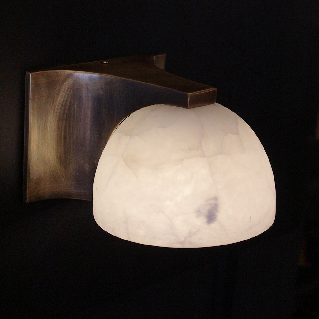 Wall-mounted light fixture with a white marble-like shade on a dark background