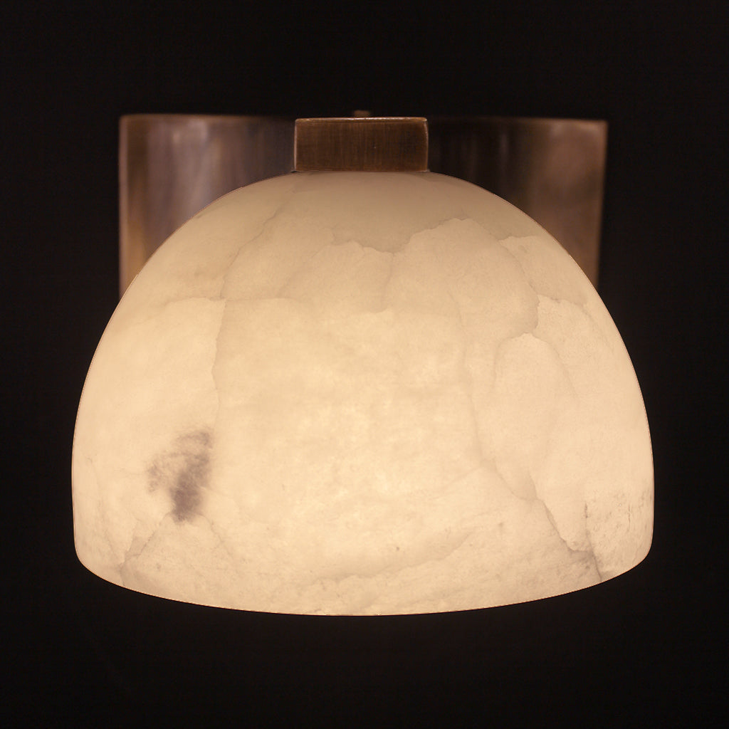 Decorative wall sconce with a textured white shade on a black background