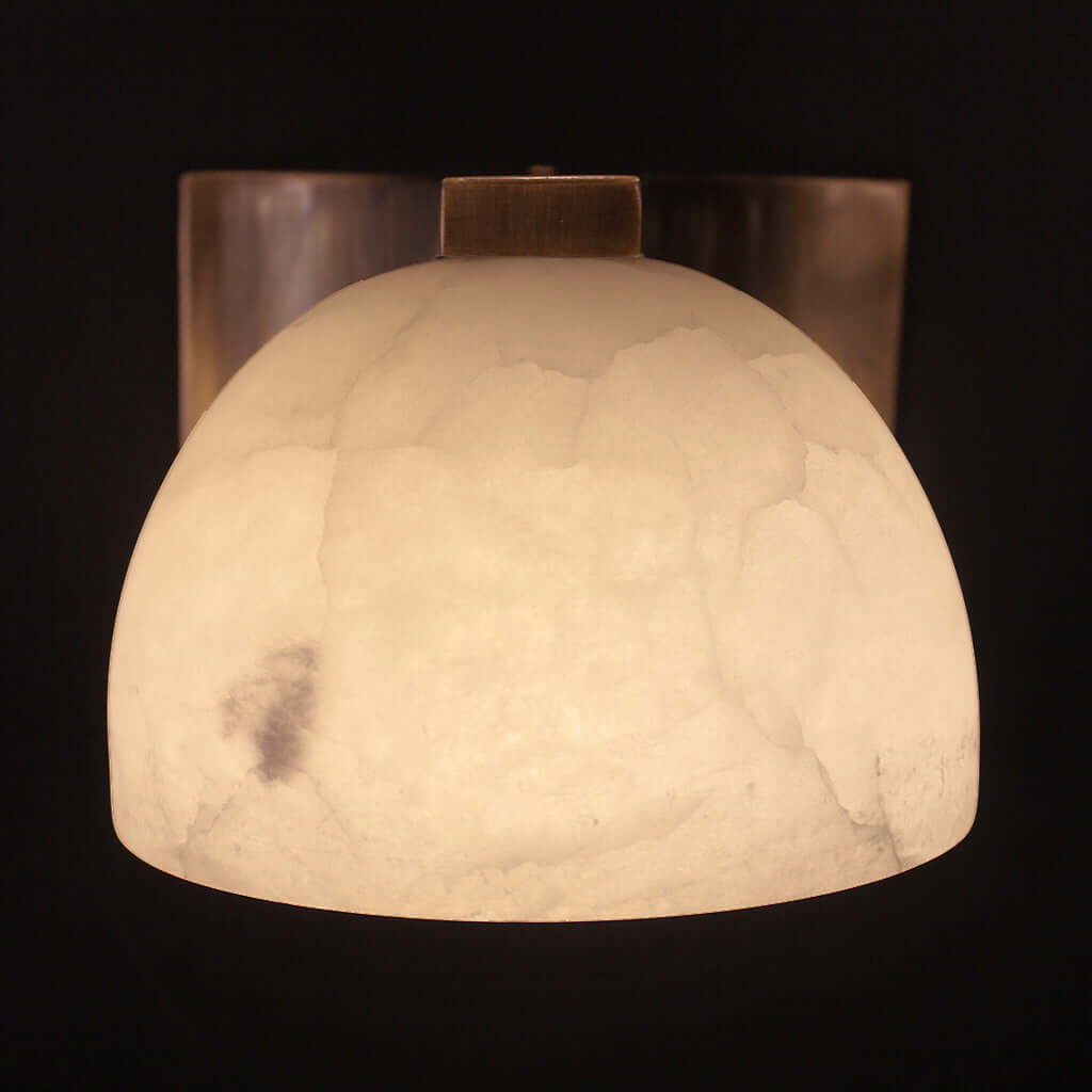 Decorative wall sconce with a textured white shade on a black background
