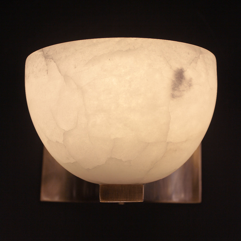 Marble-textured wall sconce with a warm glow on a black background