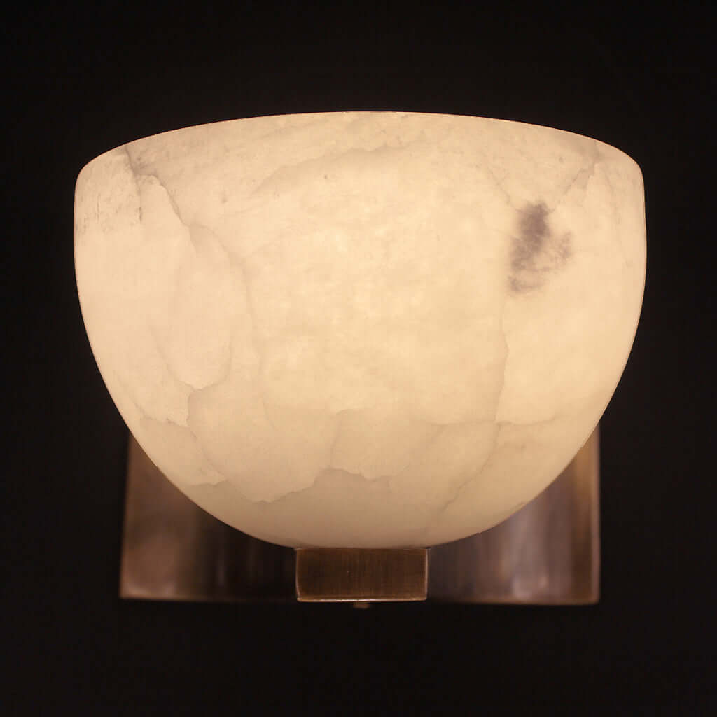 Marble-textured wall sconce with a warm glow on a black background