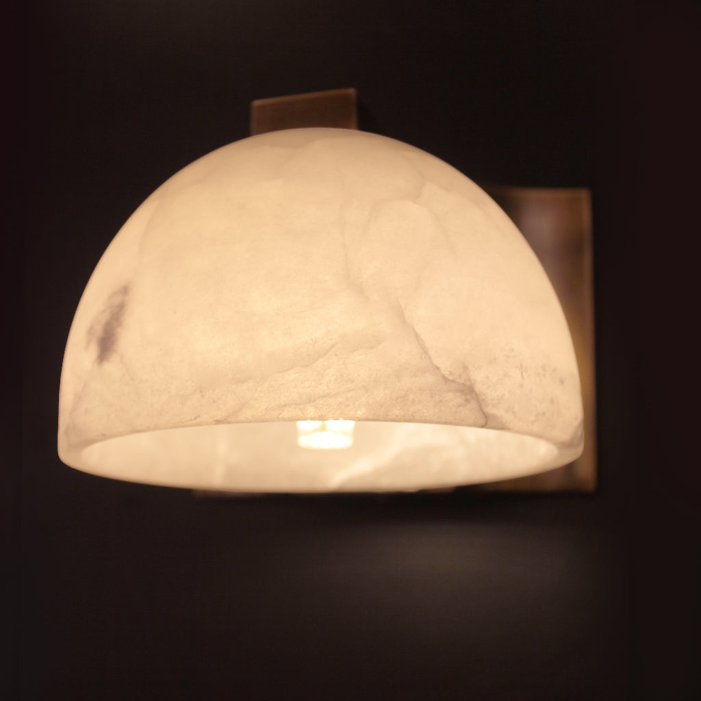 Wall-mounted light fixture with a marble-like finish on a dark background