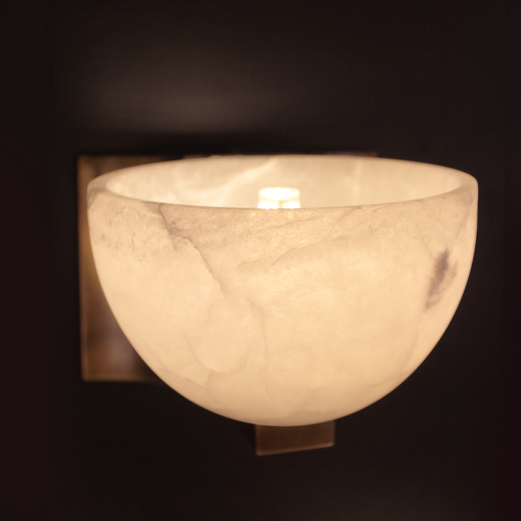 Wall-mounted light fixture with a marble-like finish on a dark background