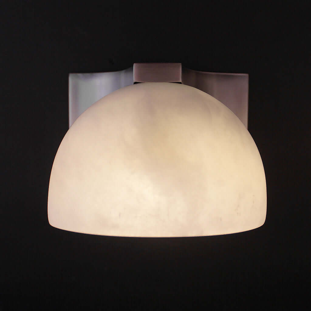 Wall-mounted light fixture with a white glass shade on a black background
