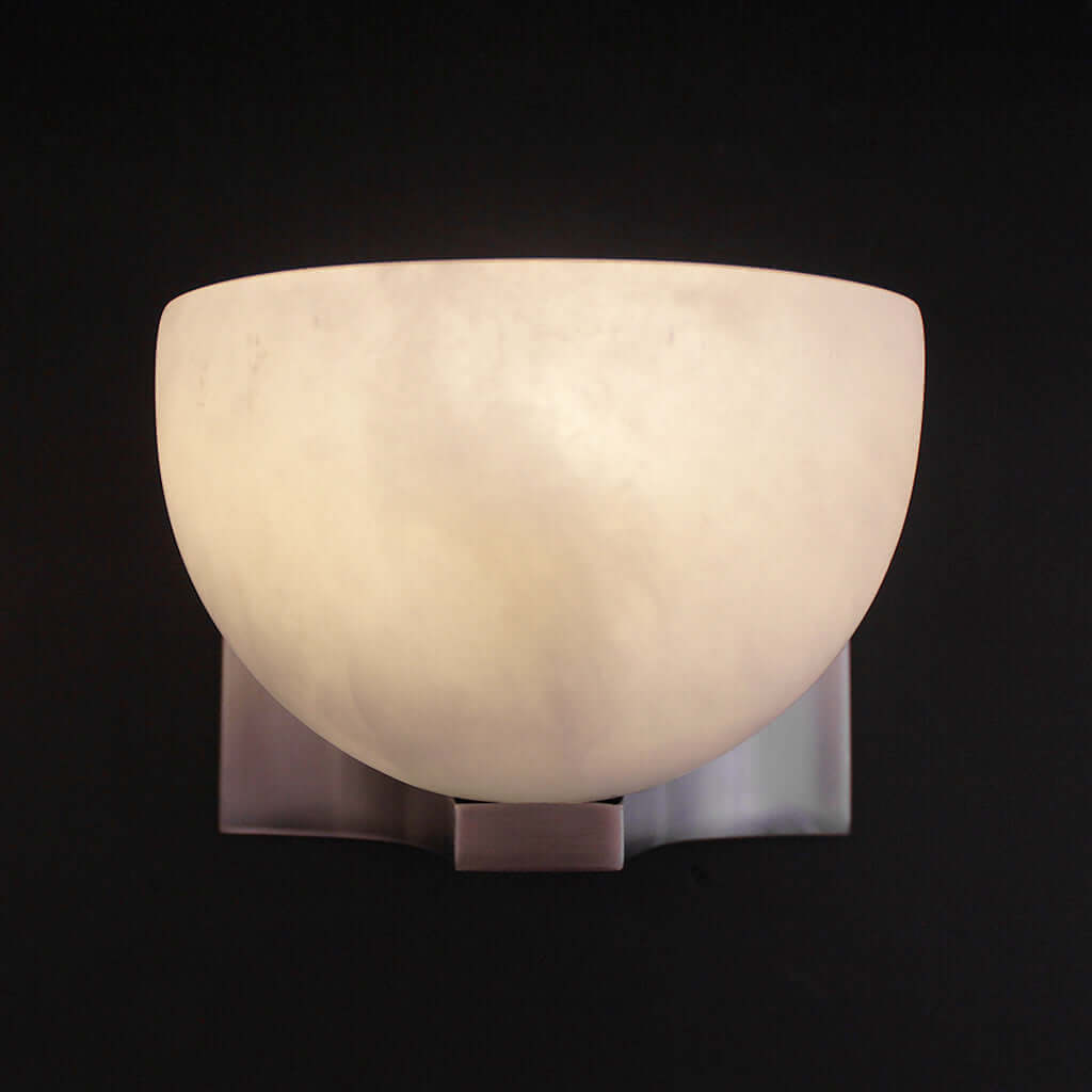 Wall-mounted light fixture with a white glass shade on a black background