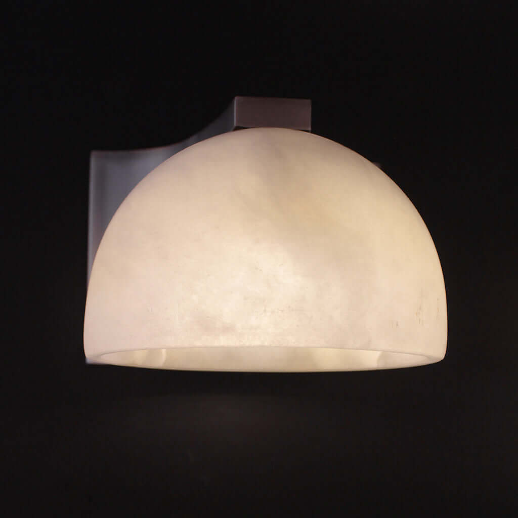 Wall-mounted light fixture with a textured stone shade on a black background