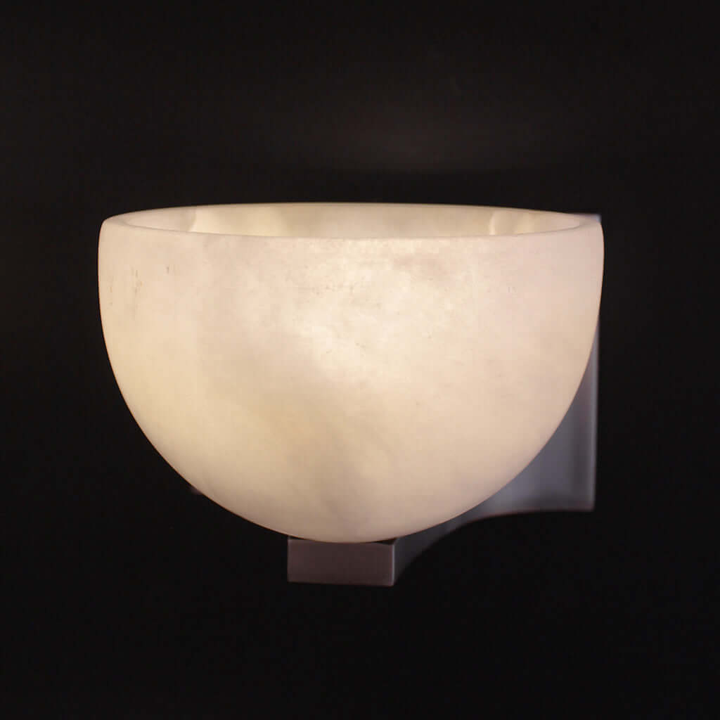 Wall-mounted light fixture with a textured stone shade on a black background