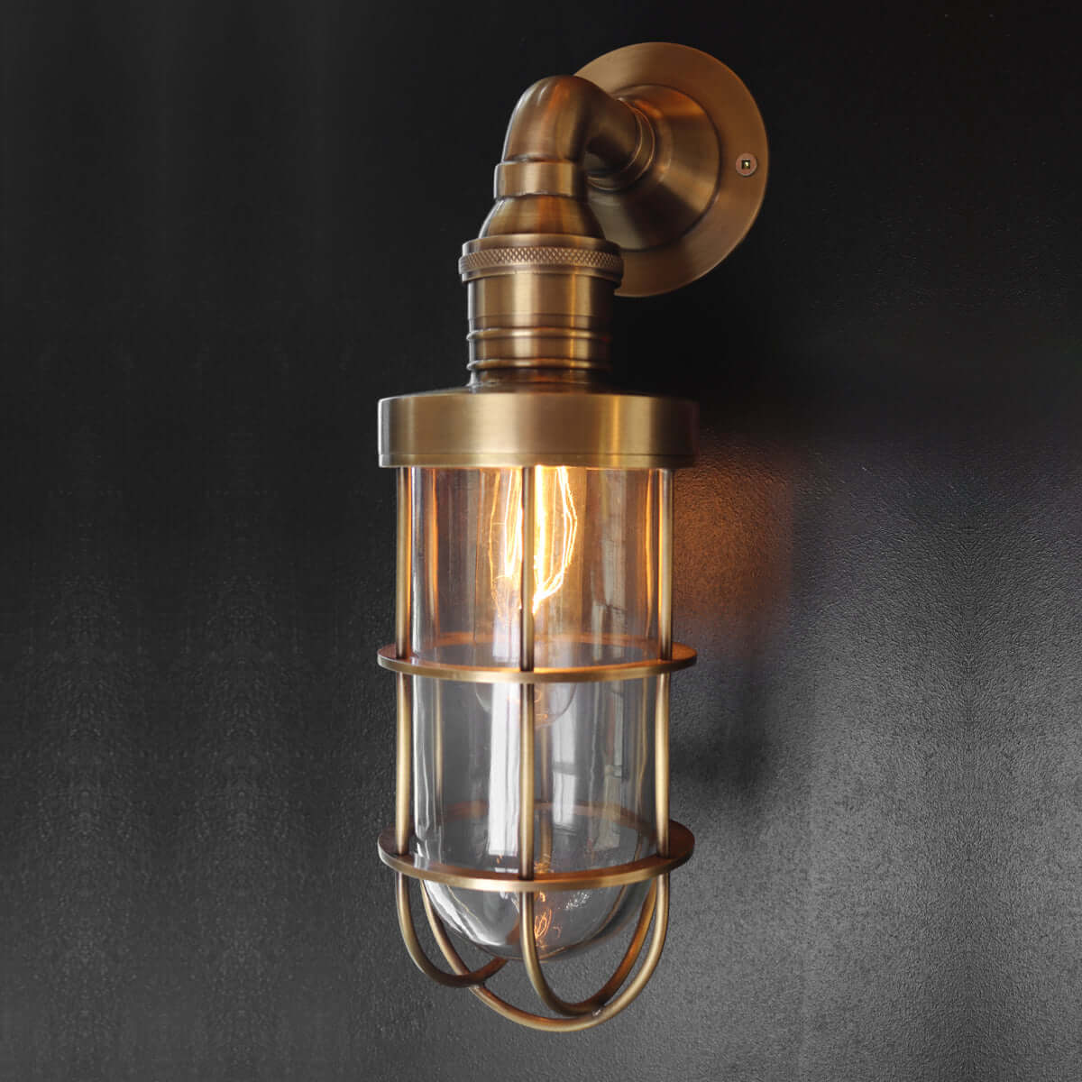 Industrial style wall sconce with brass and glass on concrete wall outside home