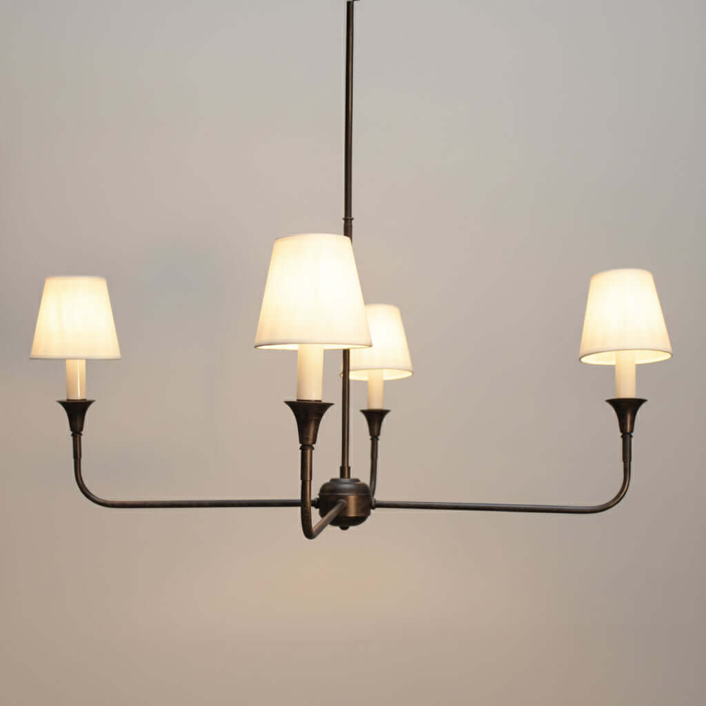 Chandelier with four lit lampshades on a dark gray background