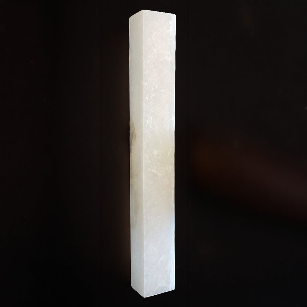 A rectangular white stone wall light with a smooth finish against a dark, solid background.