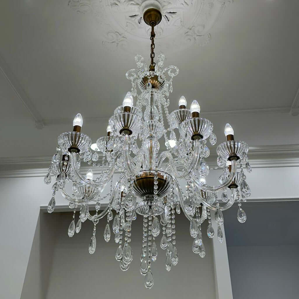 Crystal chandelier hanging from a ceiling with decorative molding.