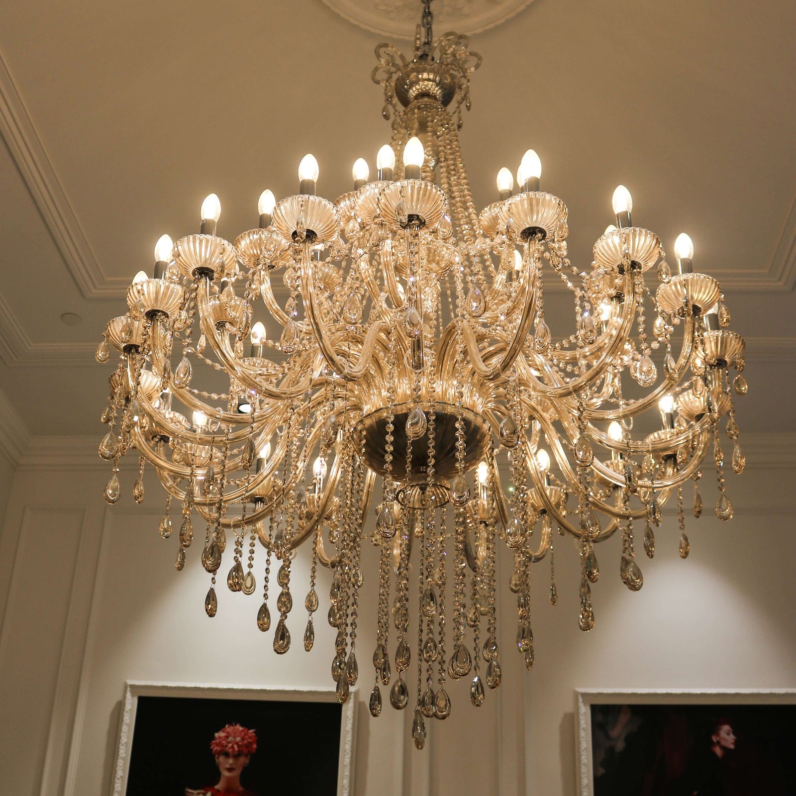 A classical-style chandelier with fluted arms and bowls, adorned with teardrop crystals, hanging from the ceiling.