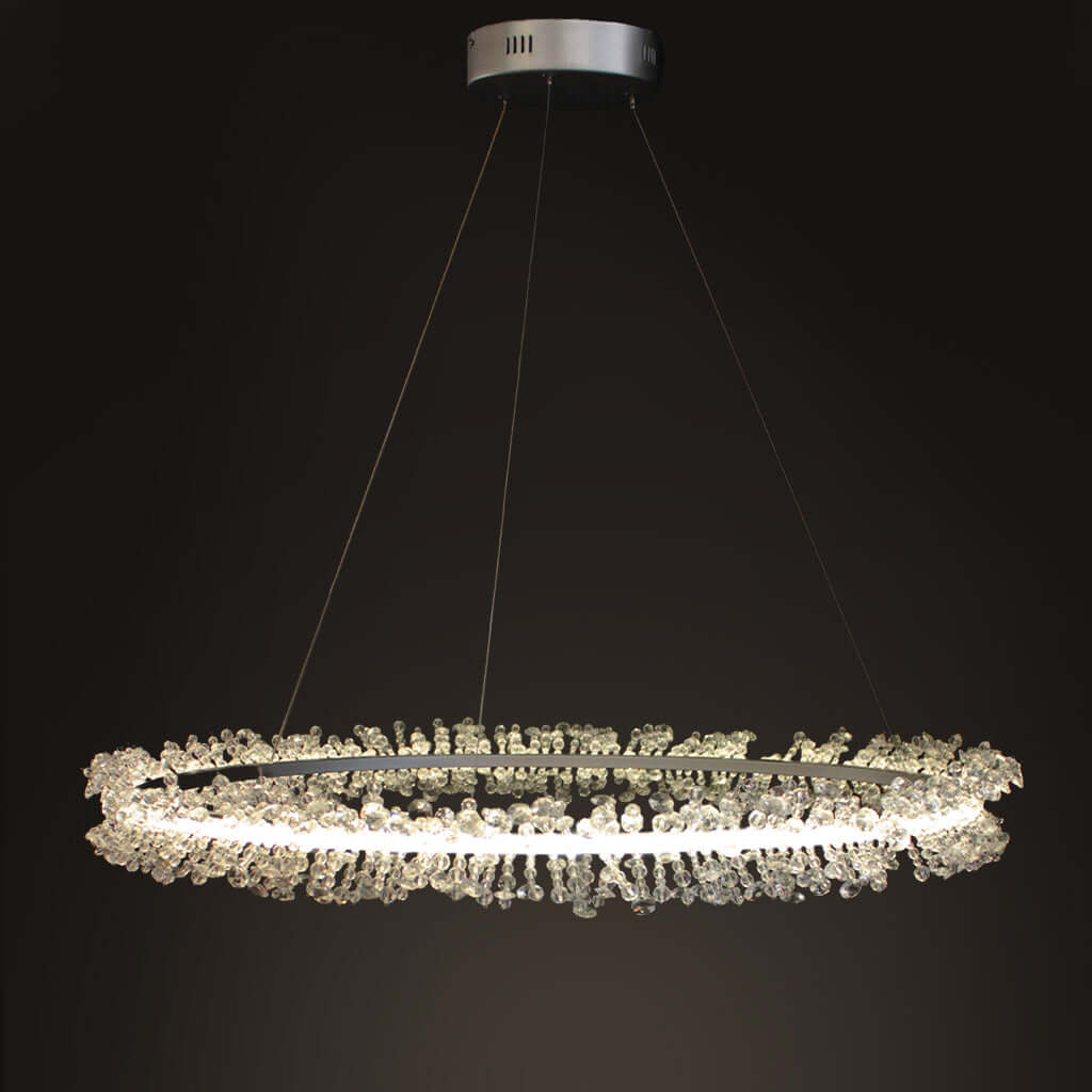 A modern circular LED chandelier with clear crystal beading, suspended from a silver ceiling canopy against a dark background.
