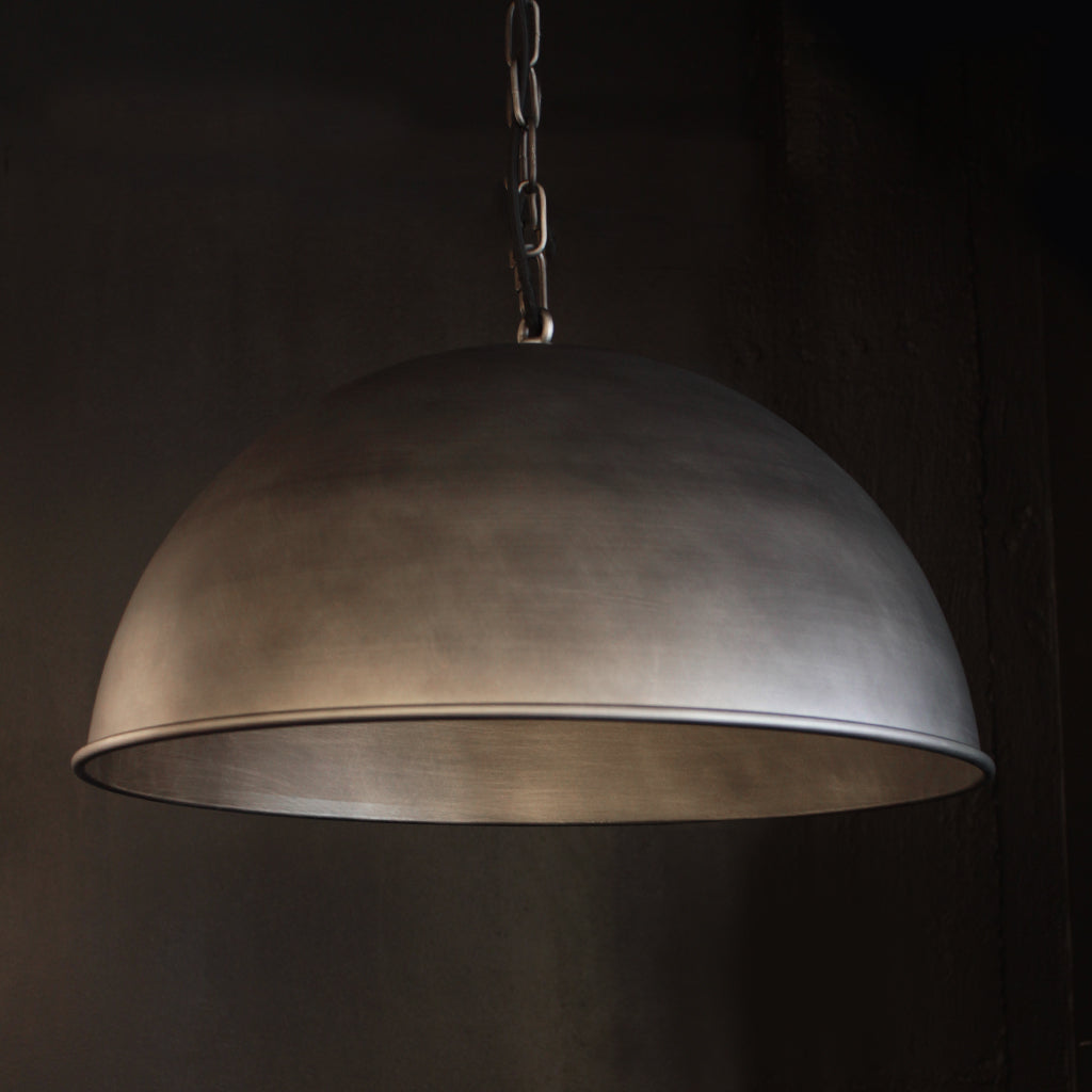 Brushed nickel industrial domed pendant light with dark background