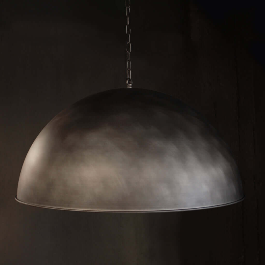 A dome-shaped pendant light with a textured, metallic nickel finish hanging from a chain against a dark background.