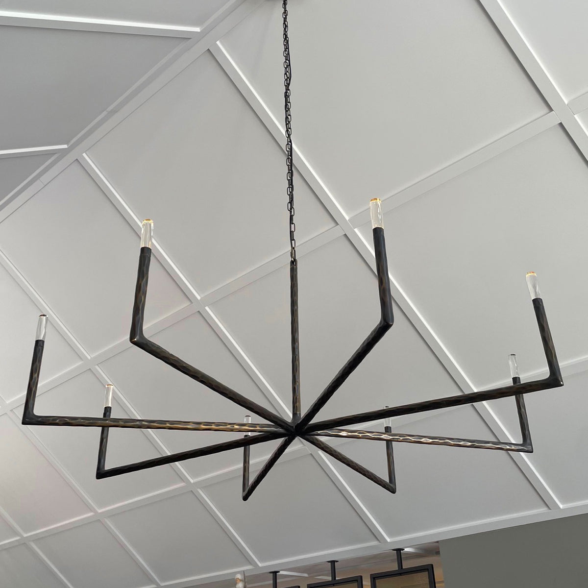 Modern black chandelier hanging from a ceiling with geometric patterns