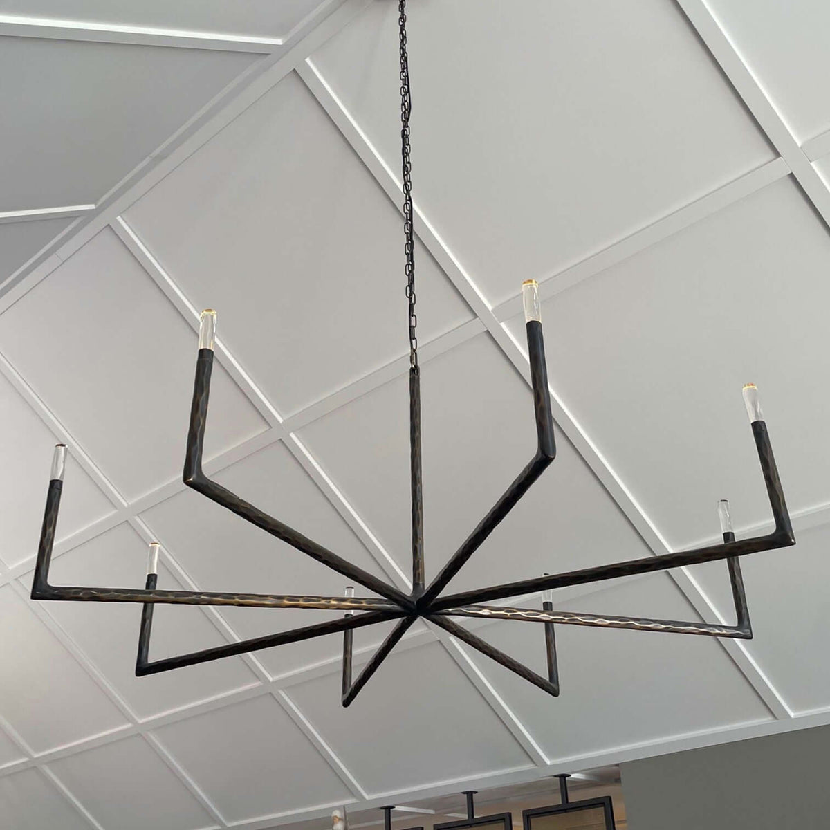 Modern black chandelier hanging from a ceiling with geometric patterns