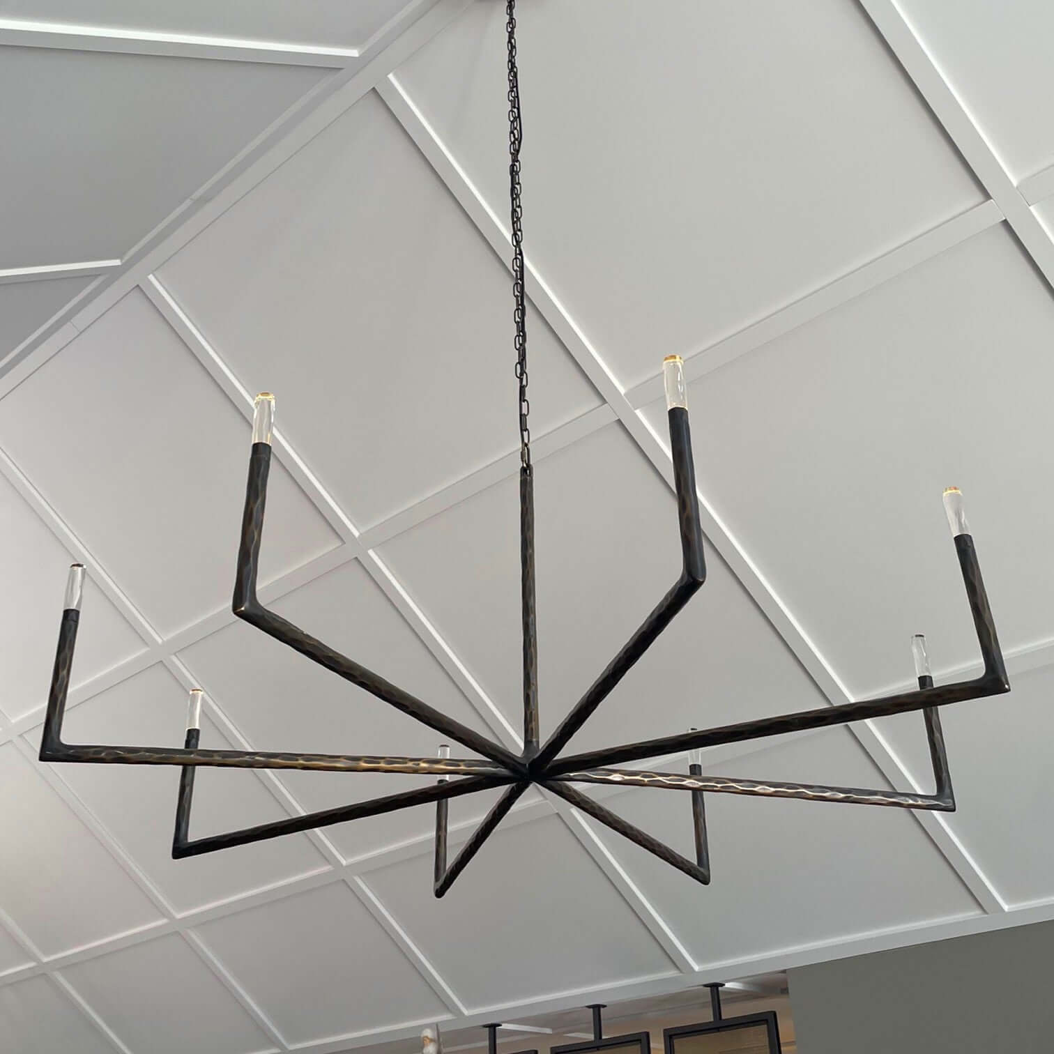 Modern chandelier hanging in a room with wooden walls and a television.