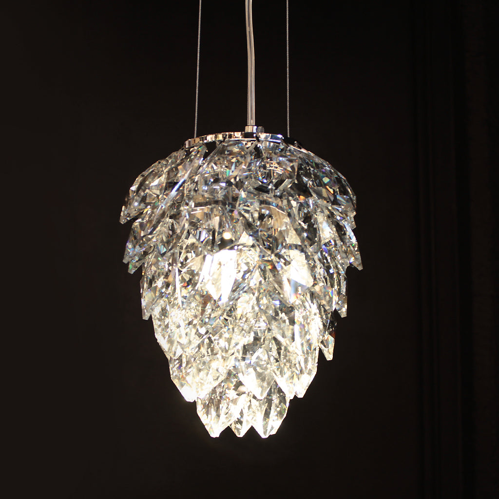 A clear crystal pendant chandelier with a leaf-like layered design, suspended against a solid black background.